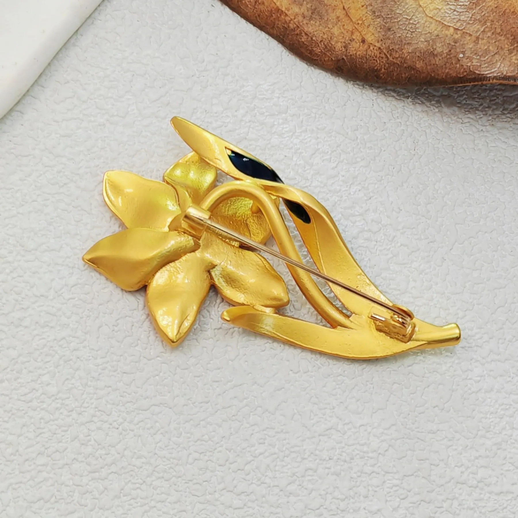 Elegant Gold - toned Enamel Flower Brooch with Crystal Centerpiece